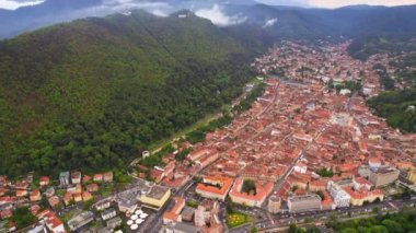 Aerial drone view of Brasov, Romania. Old city with traditional buildings, hill with lush greenery and city sign on top of it