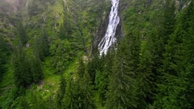 Aerial drone view of nature in Romania. Carpathian mountains with waterfall and tourists, rocky slopes with greenery, fog