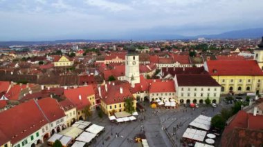 Romanya 'nın başkenti Sibiu' daki tarihi merkezin hava aracı görüntüsü. Büyük Meydan 'da Konsey Kulesi ve eski binalar, dar sokaklar, insanlar, aydınlanma