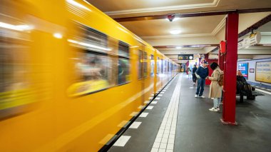 BERLİN, ALMANY - Eylül 2022: Hareket halindeki tren ve insanların bulunduğu bir yeraltı istasyonunun içi