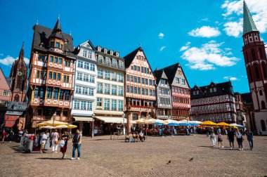 FRANKFURT, GERMANY - Eylül 2022: günbatımında Roemerberg manzarası. Eski Aziz Niklas Kilisesi 'nin olduğu meydan, kafelerde ve yarım keresteli binalarda dinlenen çok sayıda insan.