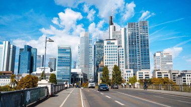 FRANKFURT, GERMANY - Eylül 2022: Şehrin ana nehir üzerindeki bir köprüden manzarası, yeşillik, insanlar, binalar ve gökdelenler