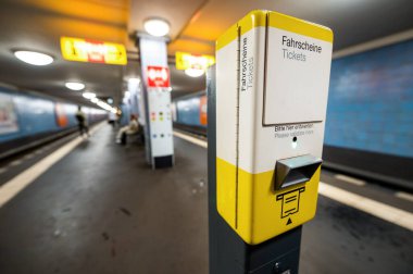 Berlin 'deki yeraltı bilet makinesi, Almanya. İstasyondakiler arka planda.