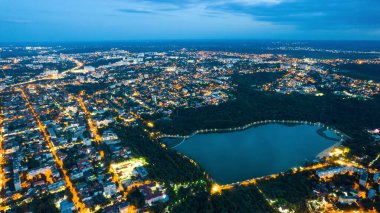 Akşam Chisinau 'nun hava aracı görüntüsü, Moldova. Yeşillik ve gölle dolu Valea Morilor parkı. Çevredeki konut binaları, aydınlanma