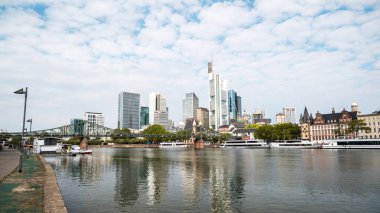 Frankfurt şehri, Almanya 'da. Köprüsü ve demirli tekneleri olan River Main, arka planda gökdelenler, diğer binalar.