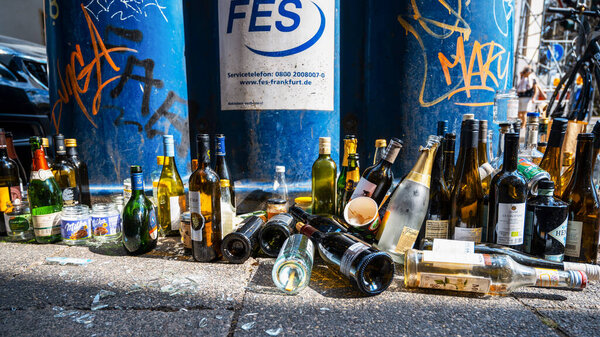 FRANKFURT, GERMANY - SEPTEMBER, 2022: Close view of multiple empty bottles on the ground near trash cans