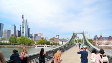 FRANKFURT, GERMANY - 11 Eylül 2022: Şehrin ana nehir üzerindeki bir köprüden manzarası, yeşillik, yürüyen insanlar, binalar ve gökdelenler