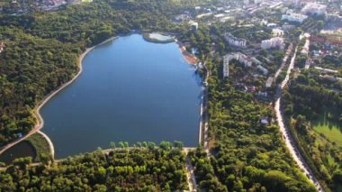 Chisinau 'nun gün batımında Moldova' daki hava aracı görüntüsü. Valea Morilor parkı yemyeşil ve tekneli göl. Çevredeki binalar, hareket halindeki arabalar.