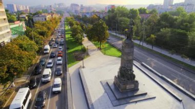 Moldova, Chisinau 'nun hava aracı görüntüsü. Bir sokak manzarası, bir anıt ve yeşillik olan bir sokak, binalar, trafik olan bir yol.