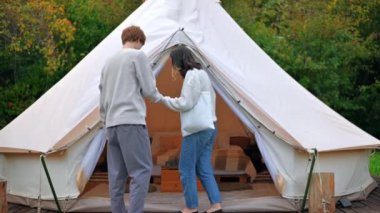 Konuşan ve glamping çadırına giren bir çift. Çevredeki yemyeşil orman