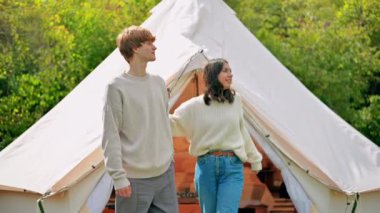 Bir çift birbirine sarılıyor ve Glamping 'de çadır terasında konuşuyor. Çevredeki yemyeşil orman