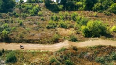 Motokros yarışında sıçrama tahtasından atlayan bir motosikletlinin hava aracı görüntüsü, çamur pisti, rali motosikleti, yeşillik. Yavaş çekim