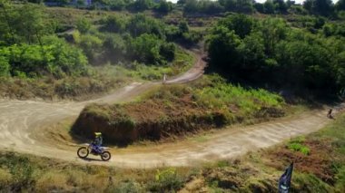 Motosikletlilerin bir motokros yarışındaki hava aracı görüntüsü, çamur pisti, rali motosikletleri, yeşillik.