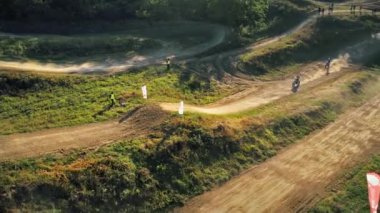 CHISINAU, MOLDOVA - SEPTEMBER, 2022: Motokros yarışındaki motosikletçilerin hava aracı görüntüsü, sıçrama tahtaları, rali motosikletleri, yeşillik ve çevresindeki insanların çamur pisti. Yavaş çekim