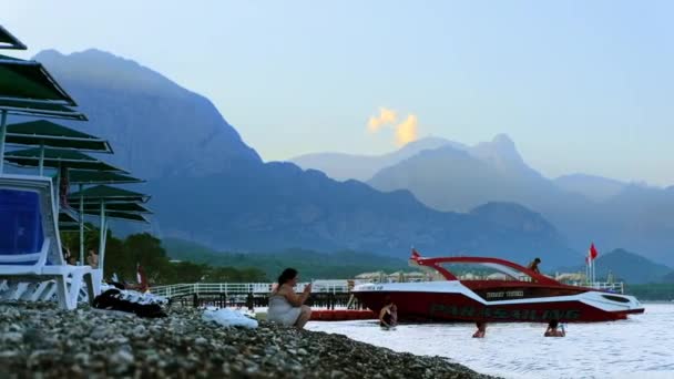 Kemer Turkey 2022年9月 日没で地中海沿岸のビーチの眺め 遠くの人 ボート 山を休める — ストック動画