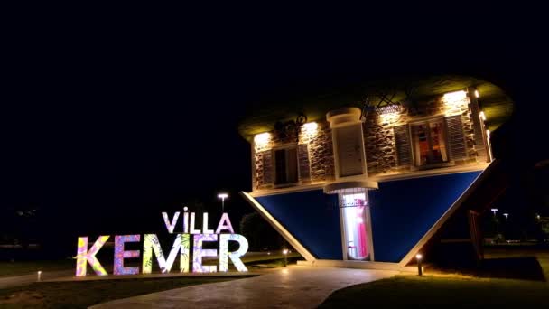 Kemer Turkey 2022年9月 それの前に看板と夜の照明を持つ反転した家の眺め 人や緑を歩く — ストック動画