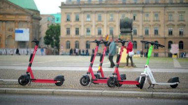 BERLİN, ALMANY - EPTEMBER, 2022: Otoparktaki Voi ve Lime elektrik paylaşım scooterlarının görüntüsü, arka planda sokak manzarası