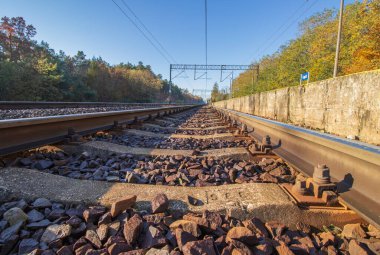 Raylara alçak bir perspektiften bakmak, raylara yakın çekim yapmak ve uykuculuk yapmak. Uzun pist inşaatı. Taşlar ve demiryolu uyuyanları yere yığıldı. Rayları tutan vidaların yakın çekimi..