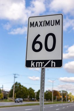 Mavi gökyüzüne karşı yolda hız limiti tabelası, Kanada 'nın Ottawa şehrinde en fazla saatte 60 km. Yolda trafik vardı.