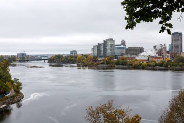 Ottawa, Kanada - 14 Ekim 2021: Ottawa Nehri ve Kanada 'nın Quebec kentinin panoramik manzarası. Portage Köprüsü. Sonbahar mevsiminde Major 's Hill Parkı' ndan renkli ağaçların renklerini değiştirdiği manzara
