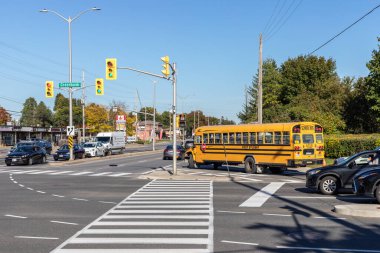Ottawa, Kanada - 6 Ekim 2021: Ottawa 'daki Baseline ve Greenbank yollarının kesiştiği trafik ışıkları, yaya geçidi, okul otobüsü ve arabaları güneşli bir sonbahar gününde sokağın ortasında.