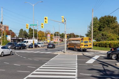 Ottawa, Kanada - 6 Ekim 2021: Ottawa 'da trafik ışıkları, yaya geçidi, okul otobüsü ve arabaları güneşli bir mevsimde sokağın ortasında bulunan Baseline ve Greenbank yollarının kesiştiği yer