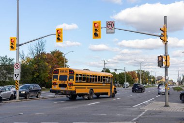Ottawa, Kanada - 6 Ekim 2021 Ottawa 'daki okul otobüsü kavşaktaki trafik ışıklarını geçiyor. Sonbahar mevsiminde, güneşli bir günde caddede kavşak ve trafik.