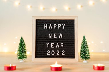 Yeni yılınız kutlu olsun. Masadaki mektup panosunda Noel süslemeleri, mumlar ve ışıklarla.
