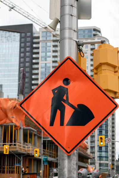 Construction orange sign near construction site against buildings — Foto de Stock