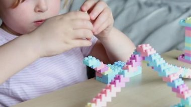 Oyuncak plastik yapı taşlarıyla oynayan, masada oturan tatlı bir çocuk..