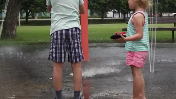Los niños pequeños que juegan en la fuente de la almohadilla del chapoteo del agua en el parque el día caliente del verano. — Vídeo de stock