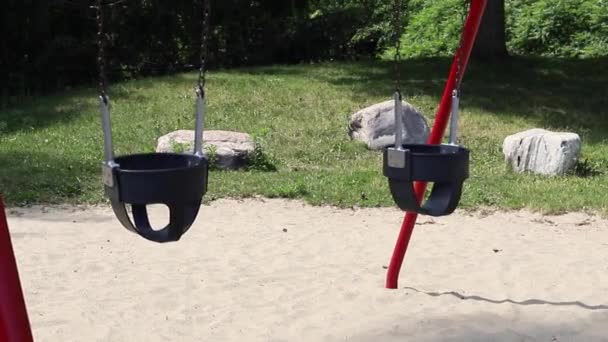 Гойдалки на дитячому майданчику в парку влітку — стокове відео