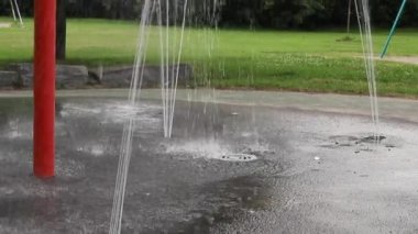 Halka açık bir parkta su sıçratma yastığı ve salıncaklar.