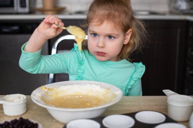 Mutfakta yemek yapan küçük bir çocuk. Küçük güzel kız evde kek yaparak para kazanıyor, yemek yapmayı öğreniyor..