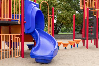 Colorful playground with slide for children in public park in summer without people
