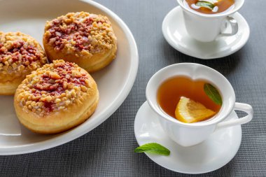 Tabaklarda tatlı yuvarlak çörekler ve masada nane çayı olan küçük bardaklar. Lezzetli kahvaltı..