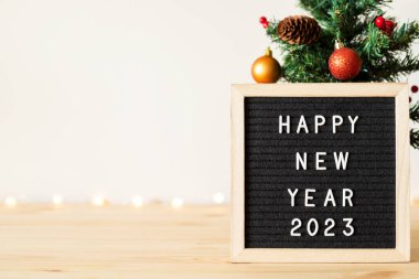 Yeni yılın kutlu olsun siyah keçeli mektup tahtası ve Noel ağacı, masa süsleri ve beyaz duvarın yanındaki ışıkların sönmesi. Metin için alanı kopyala