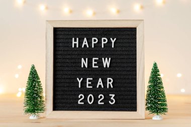 Yeni yılınız kutlu olsun. Tatil ışıkları ve ahşap masa üzerindeki küçük dekoratif Noel ağaçlarıyla birlikte. Metin için alanı kopyala