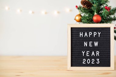 Yeni yılınız kutlu olsun. Keçeli mektup tahtası, Noel ağacı, masa süsleri ve beyaz arka planda sönmüş ışıklar. Metin için alanı kopyala