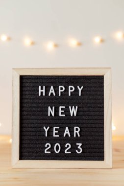 Yeni yılınız kutlu olsun. Siyah keçeli mektup tahtası ve beyaz duvarında tatil süslemeleri olan bir masa..