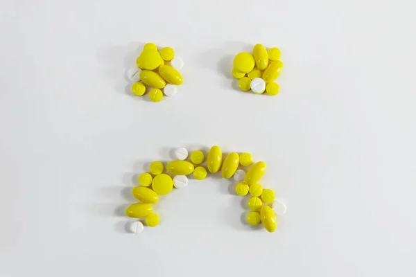 Депрессивный смайлик с желтыми таблетками. — стоковое фото
