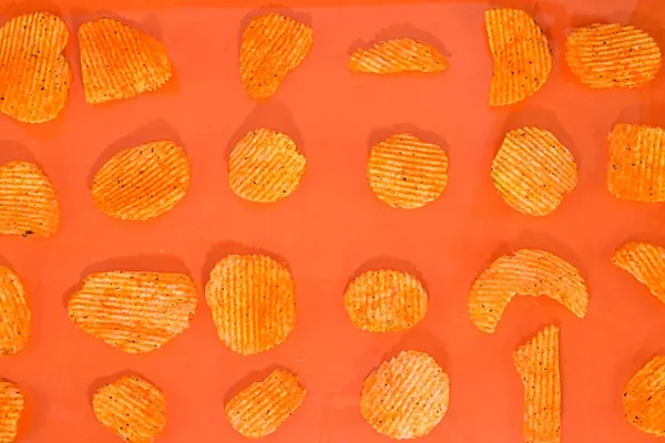 Sült krumplis rágcsálnivalók gyűjteménye narancssárga alapon. Chilli és krumpli íze van. Szemét kaja. — Stock Fotó