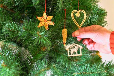 Parlak arka planda Noel ağacı süslemek. Noel ağacı süslemesi için el ele tutuşmak. Noel ve Yeni Yıl Kutlama Konsepti