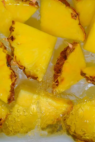 Pineapple close-up in liquid with bubbles. Slices of ripe pineapple in water. Close-up fresh slices of yellow pineapple on white background. Vertical image — Stock Photo, Image
