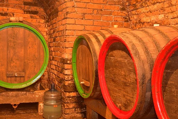 Barricas de vino apiladas en la antigua bodega de la bodega. Barricas de vino en una bodega, una antigua bodega con techos abovedados de ladrillo. Elaboración tradicional —  Fotos de Stock