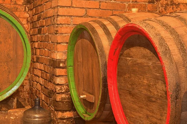 Barricas de vino apiladas en la antigua bodega de la bodega. Barricas de vino en una bodega, una antigua bodega con techos abovedados de ladrillo. Elaboración tradicional —  Fotos de Stock