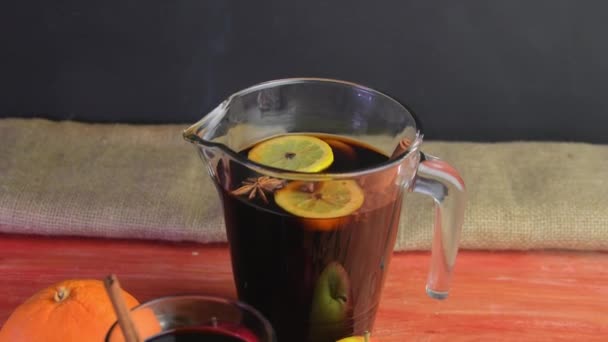Christmas hot mulled wine with cinnamon, cloves and anise star on a wooden background. Hot mulled wine for winter and Christmas on a wooden rustic table. Red hot wine in a jug