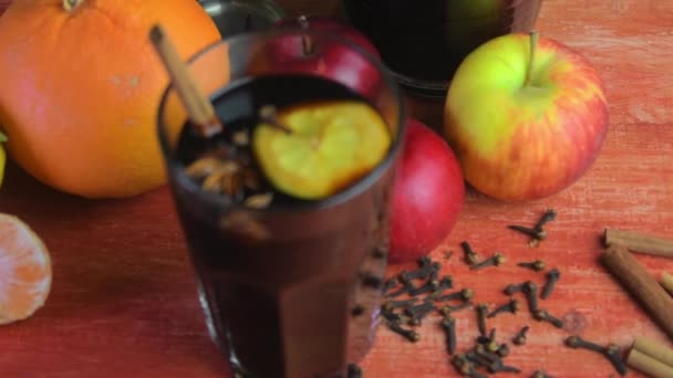 Christmas hot mulled wine with cinnamon, cloves and anise star on a wooden background. Hot mulled wine for winter and Christmas on a wooden rustic table. Red hot wine in a jug — Stockvideo