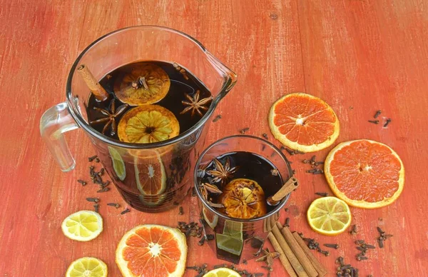 Christmas or New Year hot winter drink, spicy grog cocktail, sangria or mulled wine with tea, lemon, rum, cinnamon, anise. Rustic style. Christmas mulled red wine in a glass on a rustic wooden table — Photo