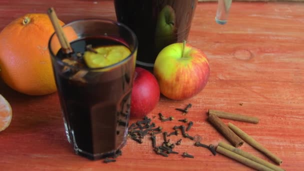 Christmas or New Year hot winter drink, spicy grog cocktail, sangria or mulled wine with tea, lemon, rum, cinnamon, anise. Rustic style. Christmas mulled red wine in a glass on a wooden table — ストック動画